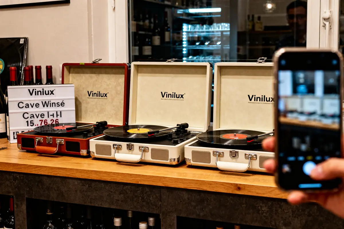 Trois tourne-disques marque Vinilux exposés sur un comptoir en bois avec vinyle.