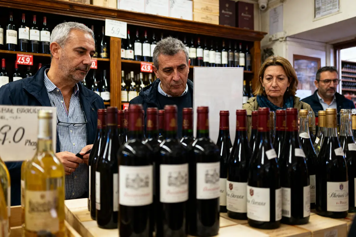 Personnes choisissant des bouteilles de vin dans un magasin bien achalandé, étiquettes et prix visibles.